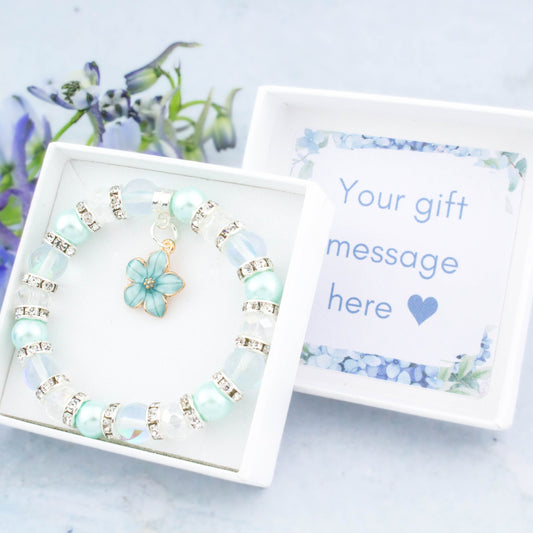 A blue flower charm bracelet with sparkly beads. It comes in a white gift box with your personalised message inside the lid.