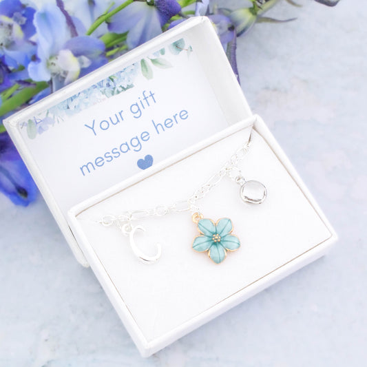 A blue flower charm bracelet for flower girls and bridesmaids. It can be personalised with an initial and birthstone and comes in a personalised gift box.