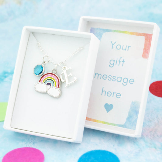 Silver rainbow charm necklace with an initial and birthstone. Presented in a gift box with a personalised message insert.