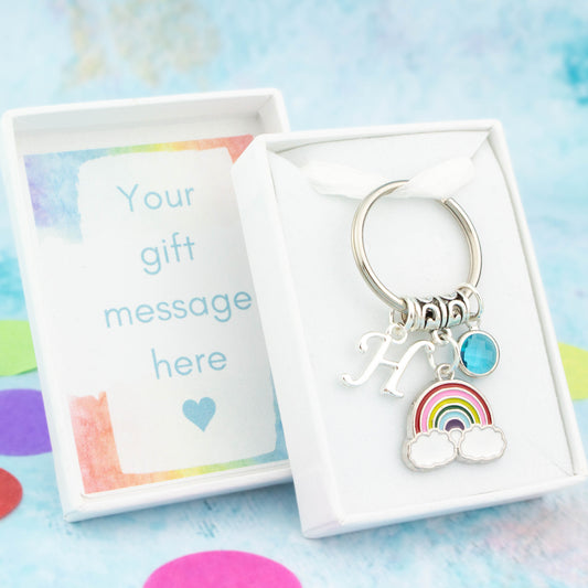 Silver enamel rainbow charm keyring with an initial and birthstone. Presented in a gift box with a personalised message insert.