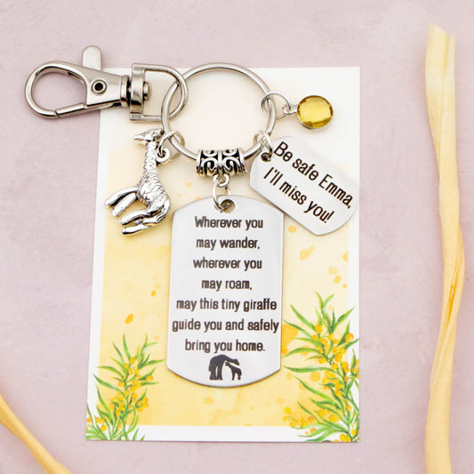 This shows the fully personalised travel giraffe keyring which includes the silver giraffe charm, the engraved quote tag which reads: “Wherever you may wander, wherever you may roam, may this tiny giraffe guide you and bring you safely home” a birthstone and a mini engraved gift message tag. It also has a clasp to attach to a bag.