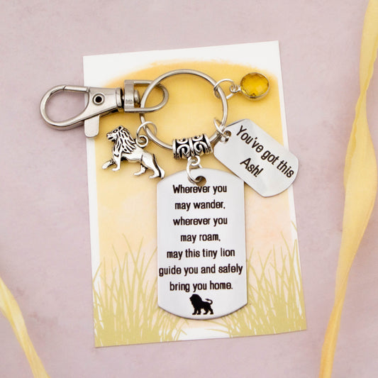 This shows the fully personalised travel lion keyring which includes the silver lion charm, the engraved quote tag which reads: “Wherever you may wander, wherever you may roam, may this tiny lion guide you and bring you safely home” a birthstone and a mini engraved gift message tag. It also has a clasp to attach to a bag.
