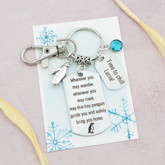 This shows the fully personalised travel Penguin keyring which includes the silver Penguin charm, the engraved quote tag which reads: “Wherever you may wander, wherever you may roam, may this tiny Penguin guide you and bring you safely home” a birthstone and a mini engraved gift message tag. It also has a clasp to attach to a bag.