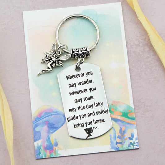 A keyring with two charms on a matching backing card. The charms are a silver Fairy and a quote charm that reads “Wherever you may wander, wherever you may roam, may this tiny Fairy guide you and bring you safely home”