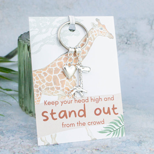 A giraffe keyring backed onto a card that says "Keep your head high and stand out from the crowd"