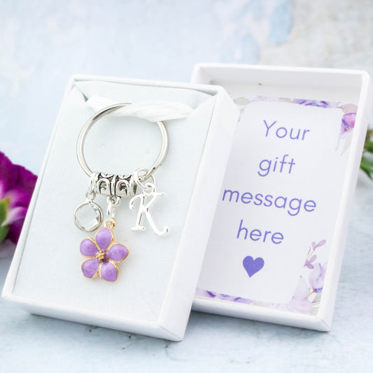 A purple flower charm keyring that can be personalised with an initial and birthstone charm. It also comes with a gift box that can have the lid insert personalised with your gift message.