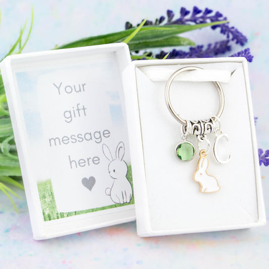 A personalised white rabbit charm keyring with an initial and birthstone. It comes in a gift box that can have your personal message printed inside the lid.