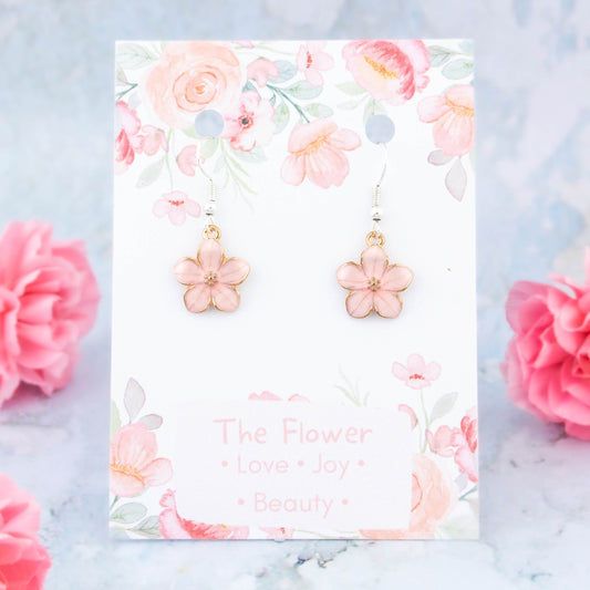 A pair of pink flower charm earrings backed onto a card with the symbolic meanings of a flower. "Love, Joy and Beauty"