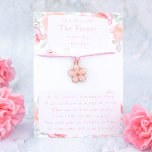 A pink flower charm bracelet. It's a wish bracelet which means it is a charm on a cord that you tie to your wrist. When your cord wears through your wish is said to come true. It comes backed on a card with the symbolic meanings of the flower, love, joy and beauty.