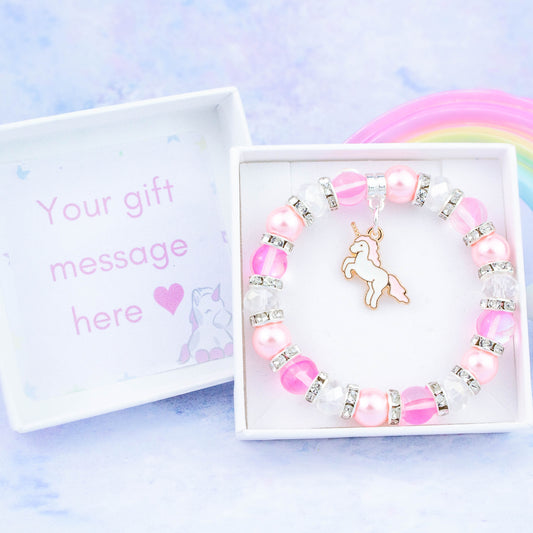 A pink unicorn charm bracelet made with pink beads. It is in a personalised gift box.