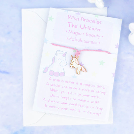 A cord with a pink unicorn charm backed onto a card. The card has a little poem about making wishes with the bracelet by tying it on and letting the cord wear through.