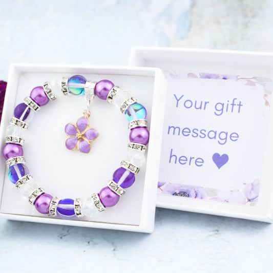 A purple flower charm bracelet with sparkly beads. It comes in a white gift box with your personalised message inside the lid.