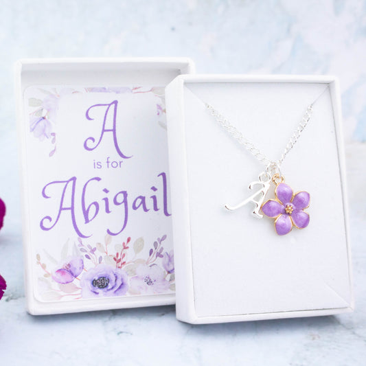 A purple flower and initial charm silver chain necklace. It comes in a white personalised gift box with the recipients name printed inside the lid.