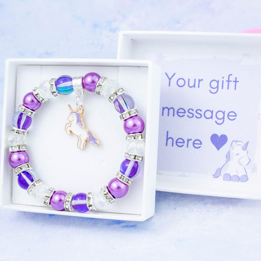 A purple unicorn charm bracelet made with purple beads. It is in a personalised gift box.