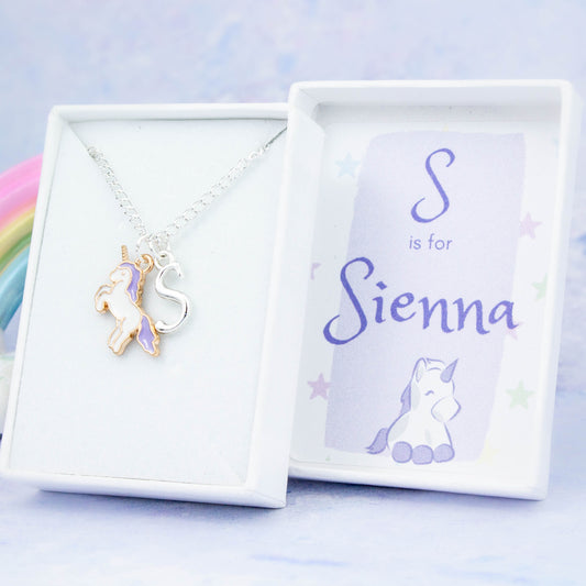 A silver chain necklace with an enamel purple unicorn pendant and initial charm. The gift box is personalised with the name of the recipient.