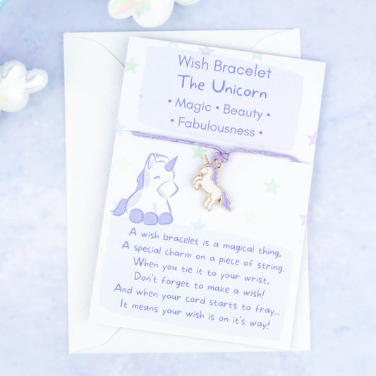 A cord with a purple unicorn charm backed onto a card. The card has a little poem about making wishes with the bracelet by tying it on and letting the cord wear through.