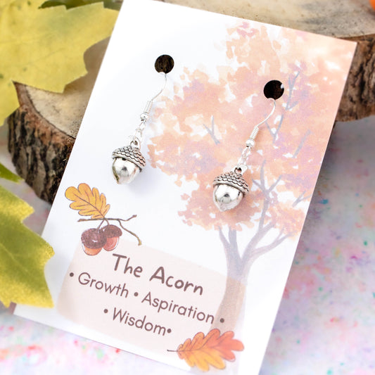 Silver 3D Acorn Charm Earrings backed onto a card with its meanings of growth, aspiration and wisdom
