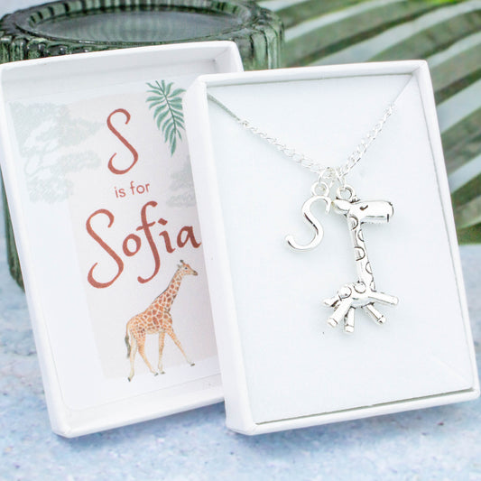A silver chain necklace with a giraffe pendant and initial charm. The gift box is personalised with the name of the recipient.