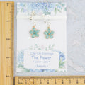 The clip on blue flower earrings shown against a ruler for the size measurements.