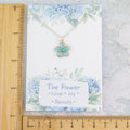 The blue flower necklace shown against two rulers to show the size measurements