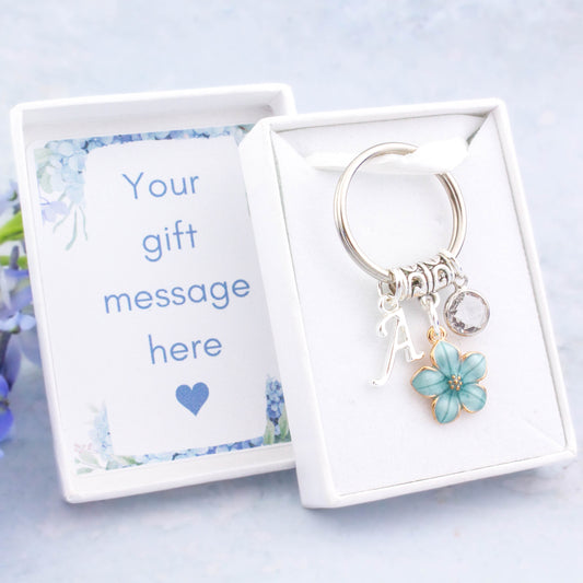 A blue flower charm keyring that can be personalised with an initial and birthstone charm. It also comes with a gift box that can have the lid insert personalised with your gift message.