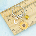 A personalised sunflower charm keyring against a ruler. 