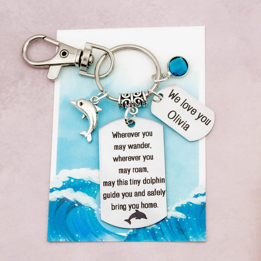 This shows the fully personalised travel dolphin keyring which includes the silver dolphin charm, the engraved quote tag which reads: “Wherever you may wander, wherever you may roam, may this tiny dolphin guide you and bring you safely home” a birthstone and a mini engraved gift message tag. It also has a clasp to attach to a bag. 