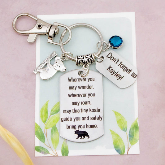 This shows the fully personalised travel koala keyring which includes the silver koala charm, the engraved quote tag which reads: “Wherever you may wander, wherever you may roam, may this tiny koala guide you and bring you safely home” a birthstone and a mini engraved gift message tag. It also has a clasp to attach to a bag. 