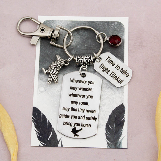 This shows the fully personalised travel raven keyring which includes the silver raven charm, the engraved quote tag which reads: “Wherever you may wander, wherever you may roam, may this tiny raven guide you and bring you safely home” a birthstone and a mini engraved gift message tag. It also has a clasp to attach to a bag. 