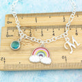 An enamel rainbow charm silver chain bracelet sitting on a ruler showing the measurements.