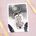 A keyring with two charms on a matching backing card. The charms are a silver raven and a quote charm that reads “Wherever you may wander, wherever you may roam, may this tiny raven guide you and bring you safely home” 