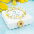 A silver and yellow sunflower  charm bracelet with sparkly beads. 