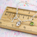 A silver 3D acorn charm silver chain bracelet sitting on a ruler showing the measurements.