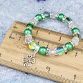 A silver and green four leaf clover charm bracelet with sparkly beads. 