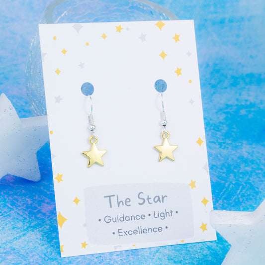 Gold Star Charm Earrings backed onto a card with its meanings of guidance, light and excellence. 