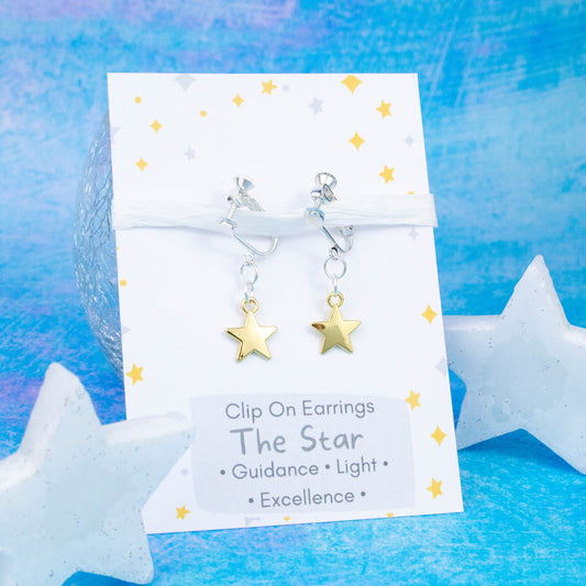 Gold Star Charm Earrings backed onto a card with its meanings of guidance, light and excellence. 