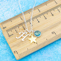 A personalised gold star charm necklace against a ruler. 
