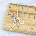 A personalised gymnastics charm necklace against a ruler. 