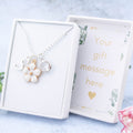 A white flower necklace personalised with an initial and birthstone. It's on a silver chain. The gift box lid can be personalised with your message.