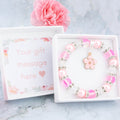 A pink flower charm bracelet with sparkly beads. It comes in a white gift box with your personalised message inside the lid.