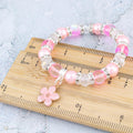 Elasticated beaded flower bracelet sitting on a ruler to show the measurements.