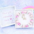 A pink unicorn charm bracelet made with pink beads. It is in a personalised gift box.