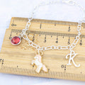 A personalised pink unicorn charm bracelet against a ruler.