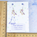 Purple Unicorn Charm earrings shown against a ruler. 